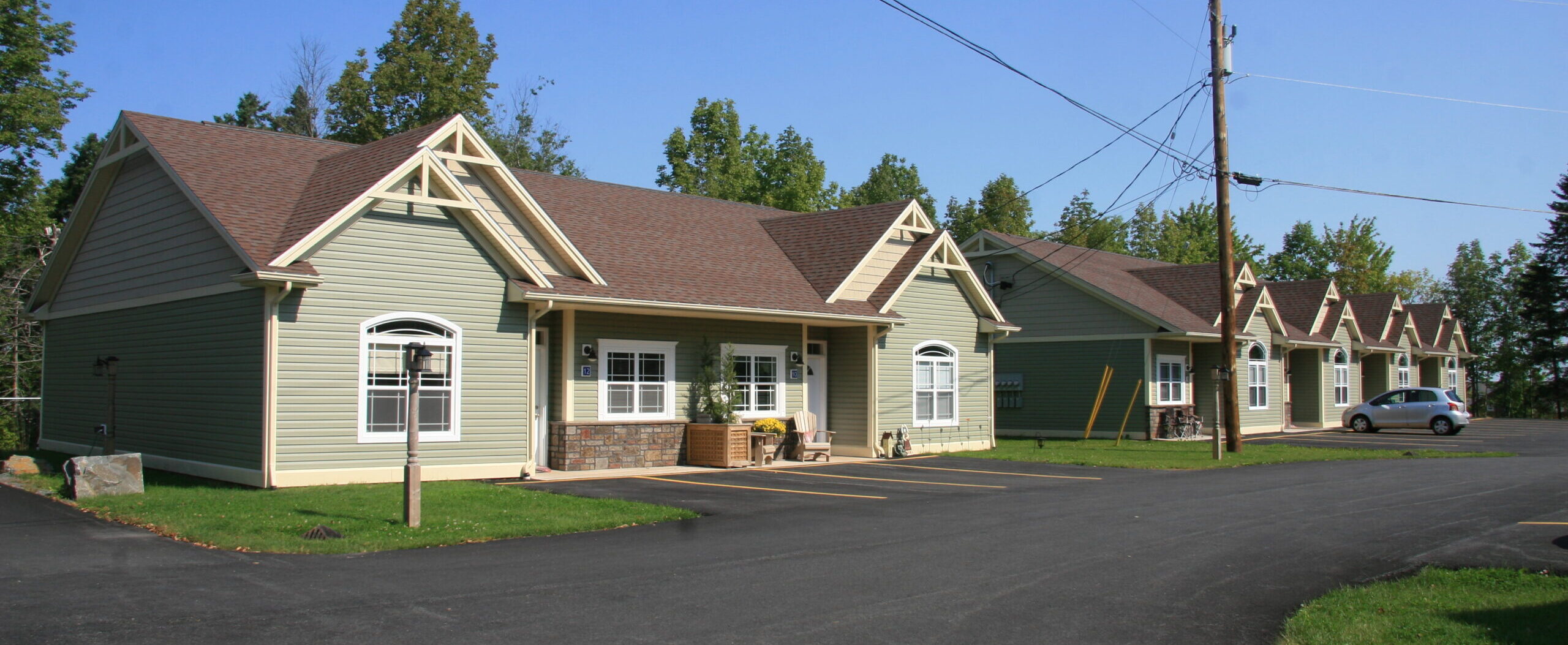 A row of olive green townhouses with brown rooves.