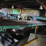 Thumbnail of http://Interior%20of%20Warehouse,%20with%20milling%20equipment%20processing%20logs.