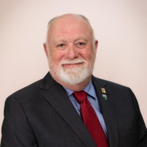 Councillor Carl MacPhee, a smiling man with light skin, white hair, white beard, and brown eyes