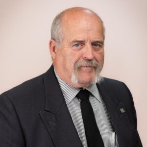 Councillor Cecil Dixon, a man with light skin, grey hair, a grey horseshoe mustache, and blue eyes